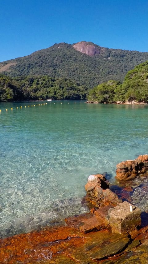Água calma e transparente da Enseada de Araçatiba, boa para caiaque e stand up, com a montanha da Ilha Grande ao fundo