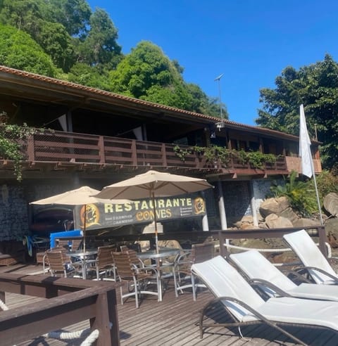 Deck do Restaurante Convés de dia, com espreguiçadeiras, guarda-sóis e a placa do restaurante